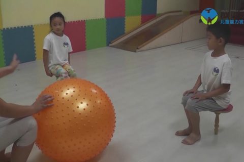 在独脚凳上抛接和踢大龙球